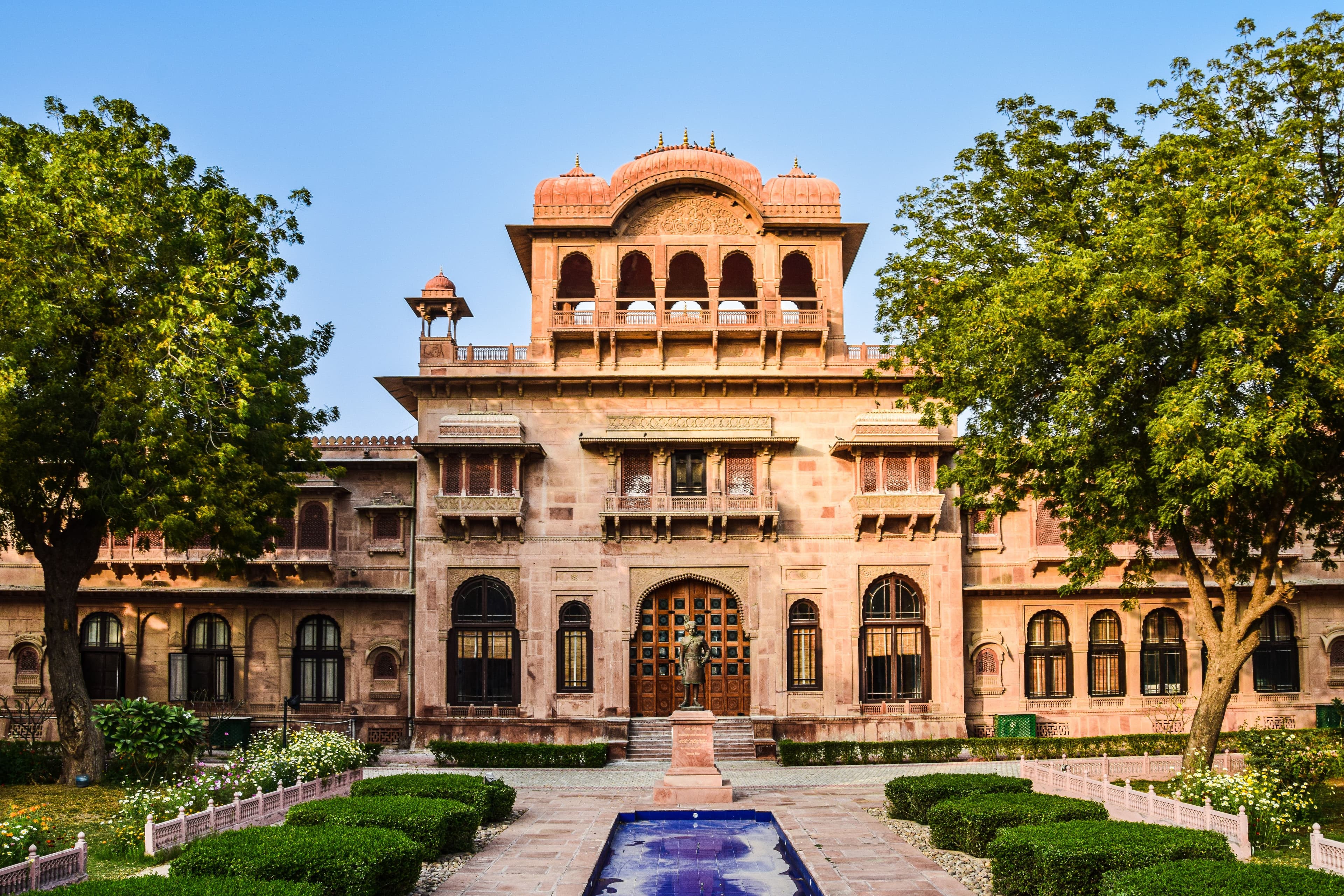 Floating marble palace hotel reflecting in calm lake waters surrounded by Aravalli hills